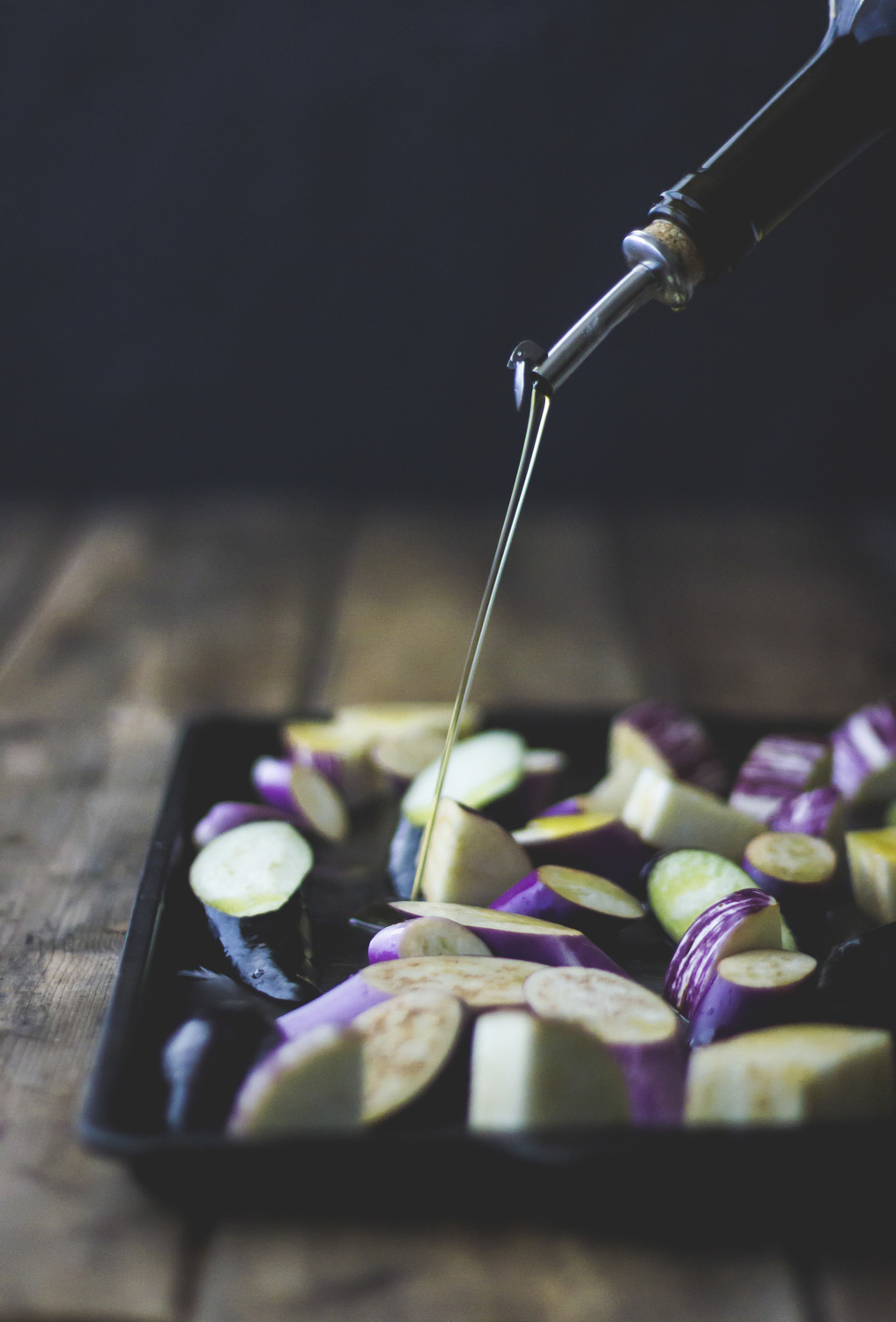 Eggplant. Oil being drixxled over sliced eggplant.